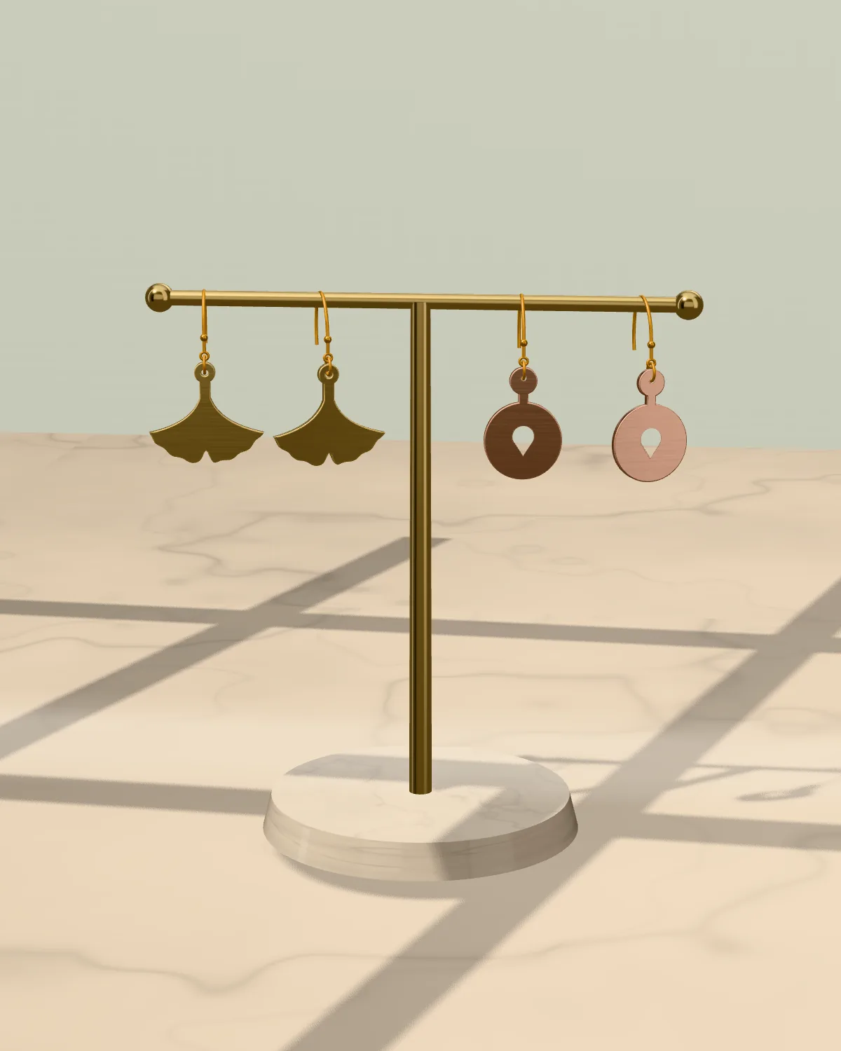 Two pairs of earrings hanging from a brass earring stand